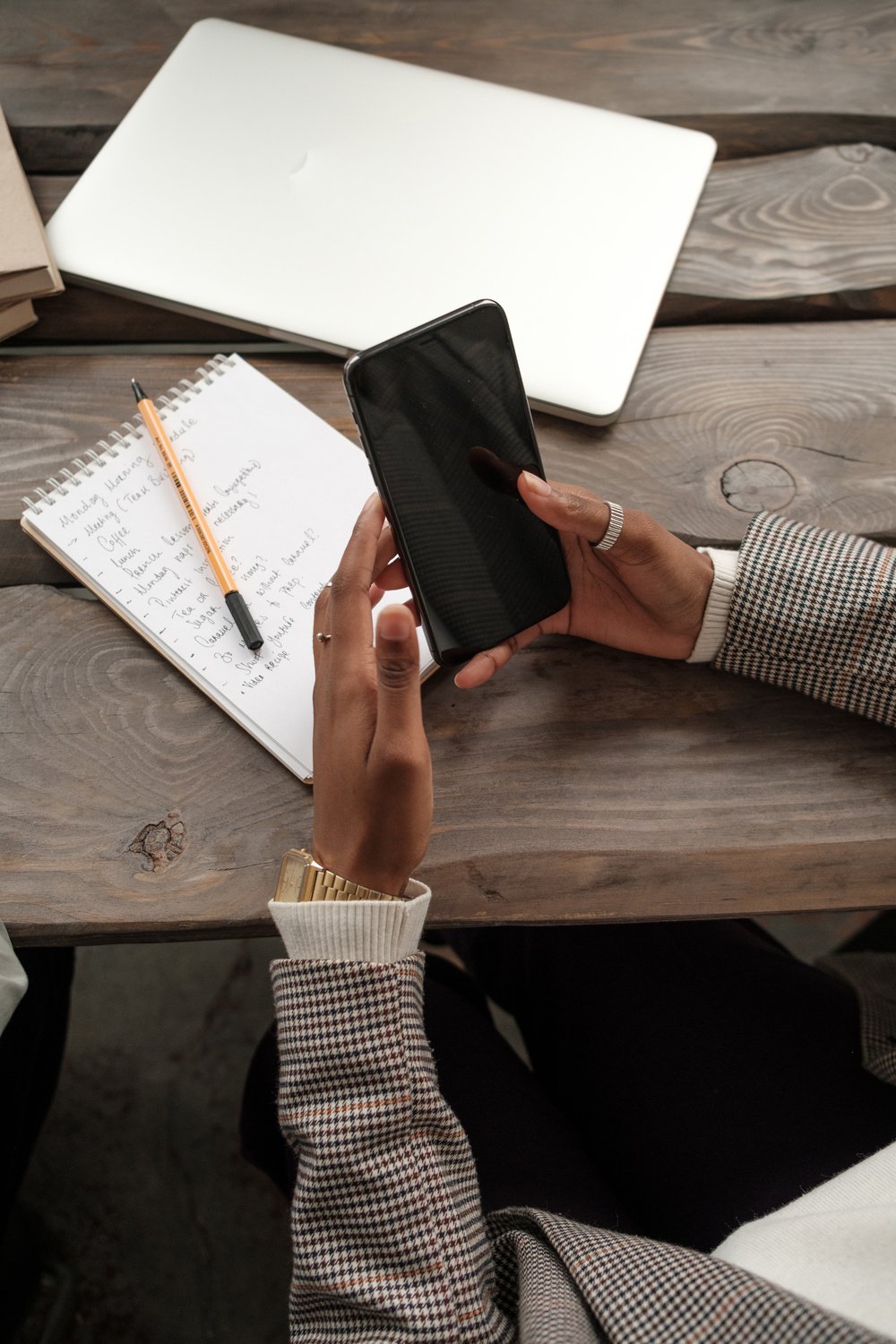 Woman Using Smartphone While Writing Notes